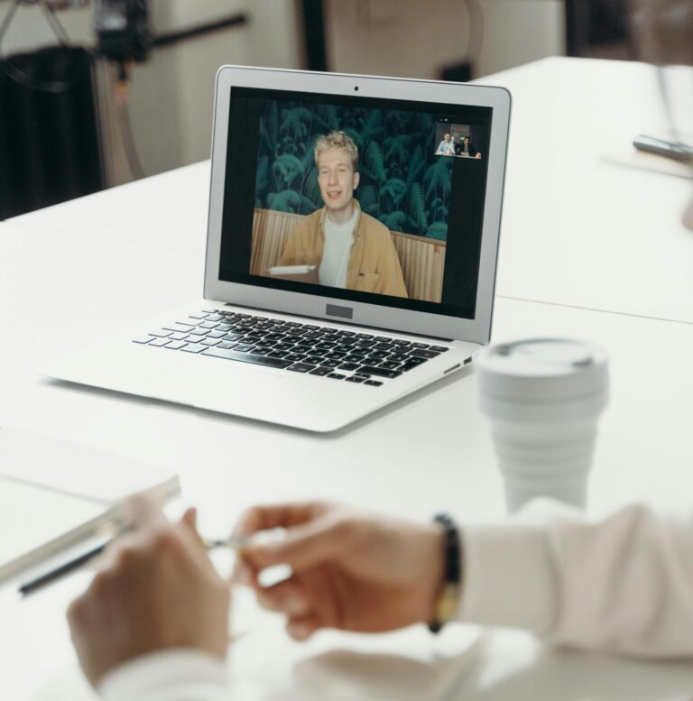Professional virtual meeting with focus on laptop screen showing a video call participant.